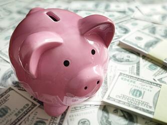 piggy bank on top of dollars